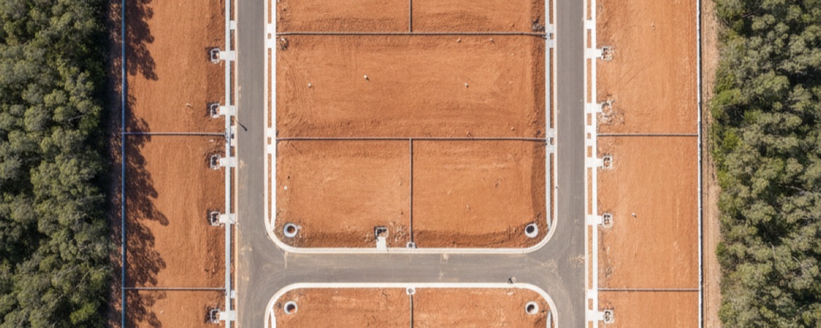 Aerial view of top-down aerial of freshly subdivided residential land, empty lots and new kerbing, no houses
